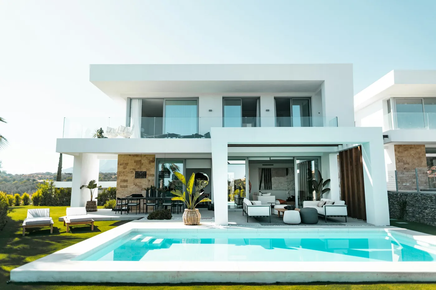 A photo from the listing: a white two-storey contemporary home with a covered alfresco, an upper terrace, a lawn and a pool